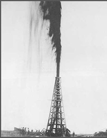 Black and white photograph of a gushing oil derrick at Spindletop.